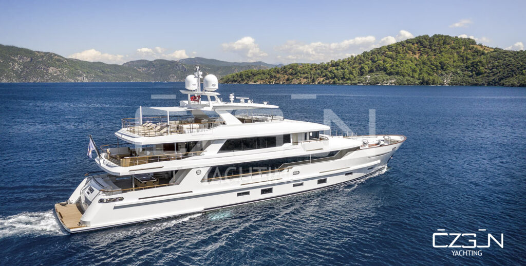 Luxury yachts anchored in the turquoise waters of Bodrum harbor with Bodrum Castle and whitewashed houses in the background.