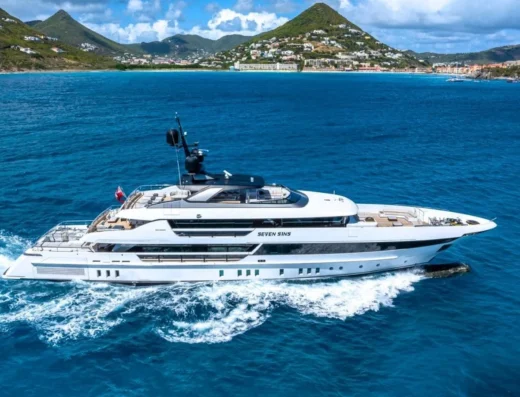 Luxury mega yacht Seven Sins anchored in the Mediterranean, showcasing sleek design and opulent outdoor lounging areas.